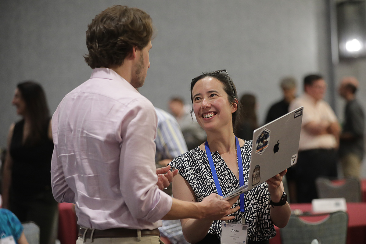 Two people with a laptop chatting and smiling at the 2026 Cottrell Scholars Conference