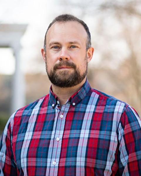 portrait of professor Timothy Atherton wearing a blue and red plaid shirt and smiling